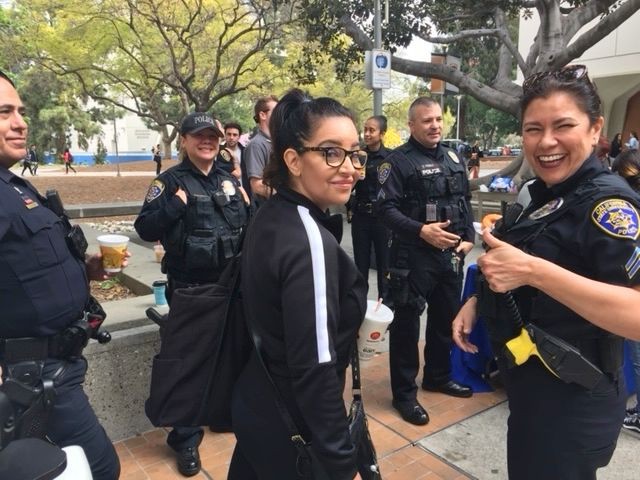 Smiling woman and group of police officers outside on a busy day.